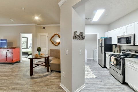 a kitchen and living room with a stove refrigerator and microwave